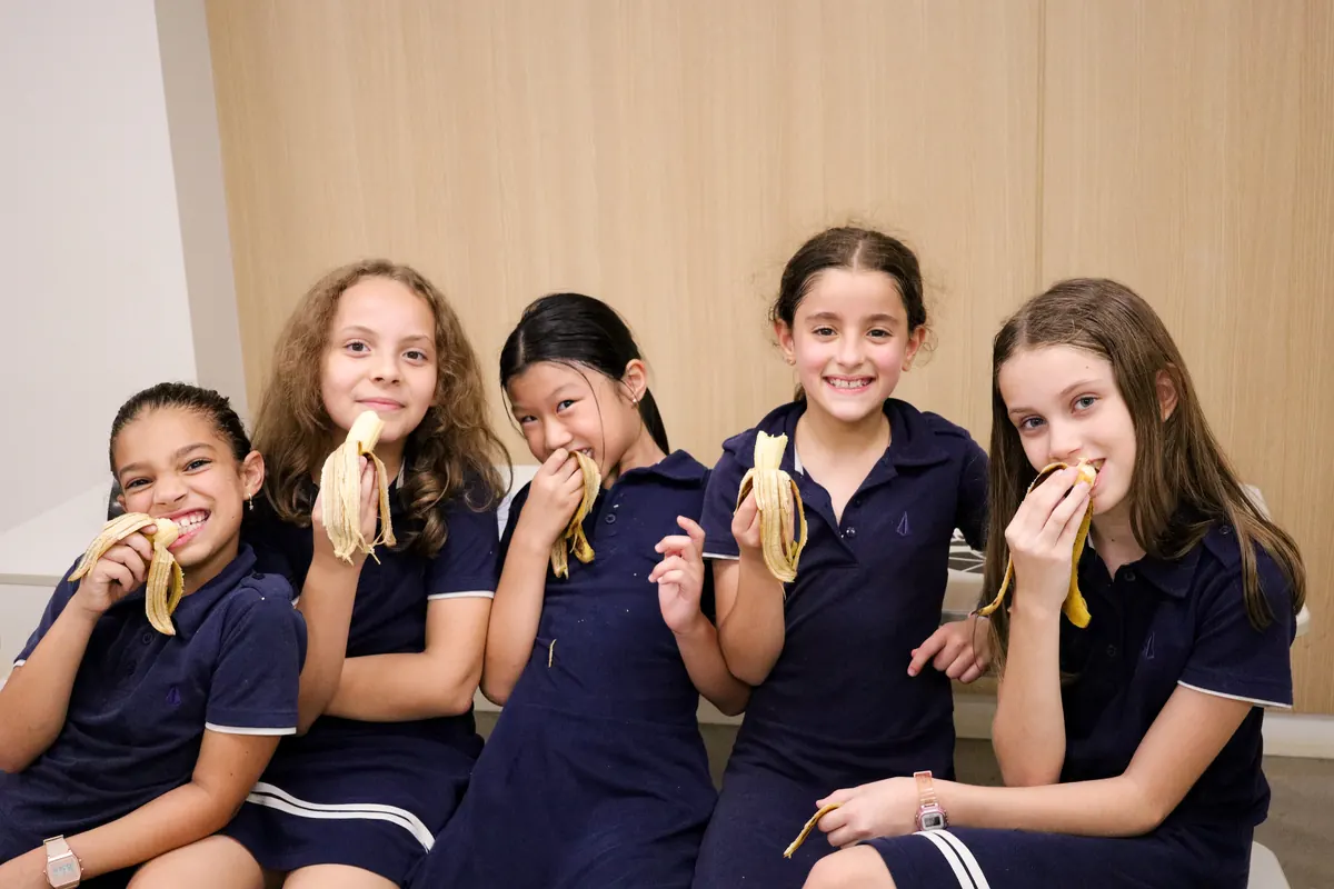 Grupo de alunas comendo banana no lanche