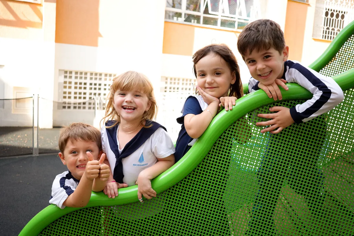 Quatro crianças da Educação Infantil fazendo joinha no tobogã do parque
